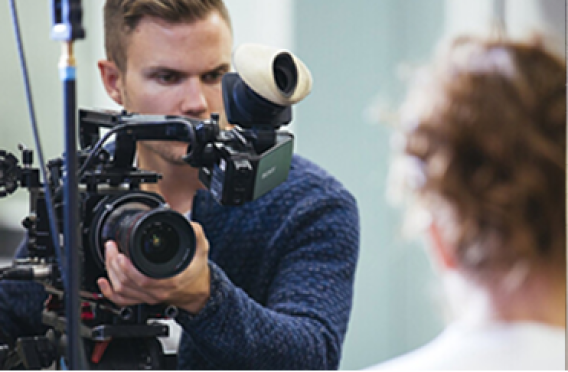 Professional videographer handling advanced camera gear during recording session.