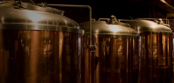 Large stainless steel fermentation tanks inside a brewery or production facility.
