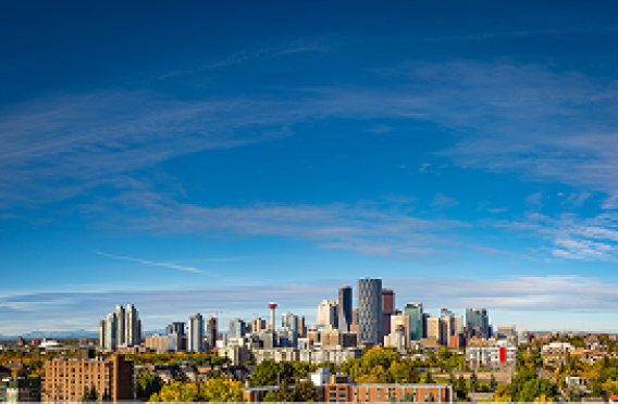 Panoramic view of Calgary’s downtown skyline under a bright blue sky.