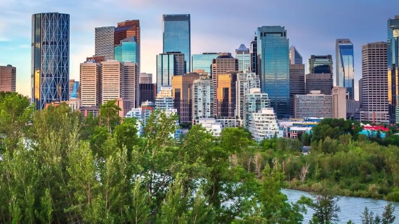 Calgary skyline rising above trees and a river in the foreground.