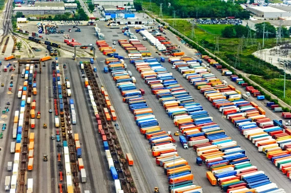 Aerial view of an intermodal yard with rail lines, trailers, and colorful shipping containers.