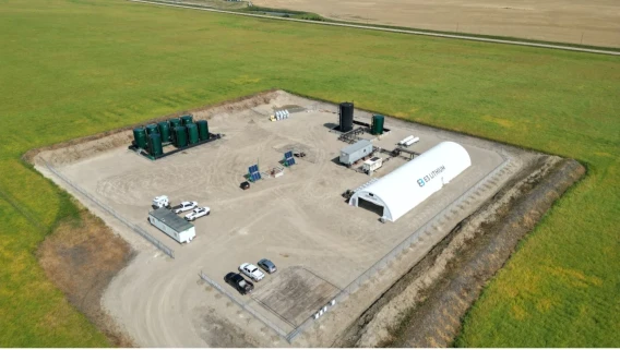 Aerial view of a lithium processing site with tanks, vehicles, and buildings in an agricultural landscape.