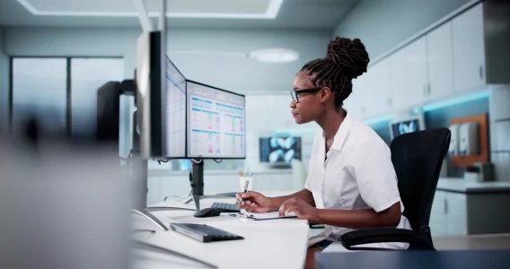 Medical professional reviewing data across dual monitors at a clinical workstation.