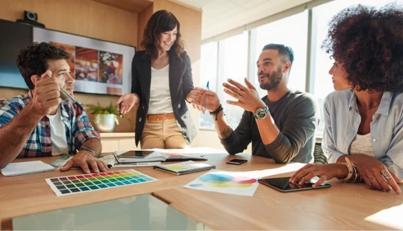 Creative team members discussing ideas around a conference table during an office meeting.