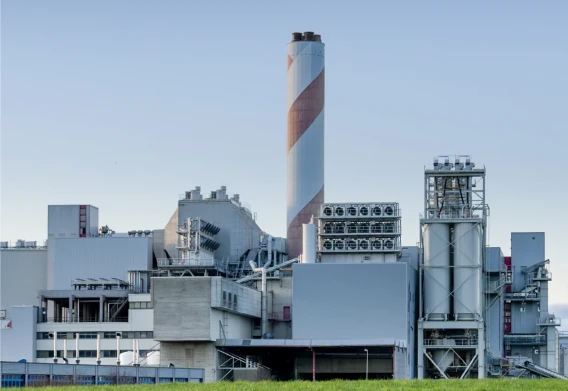 Industrial power plant facility with smokestack and processing structures under a clear sky.