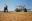 Two people stand in a field beside autonomous agricultural equipment, reviewing data on a tablet.