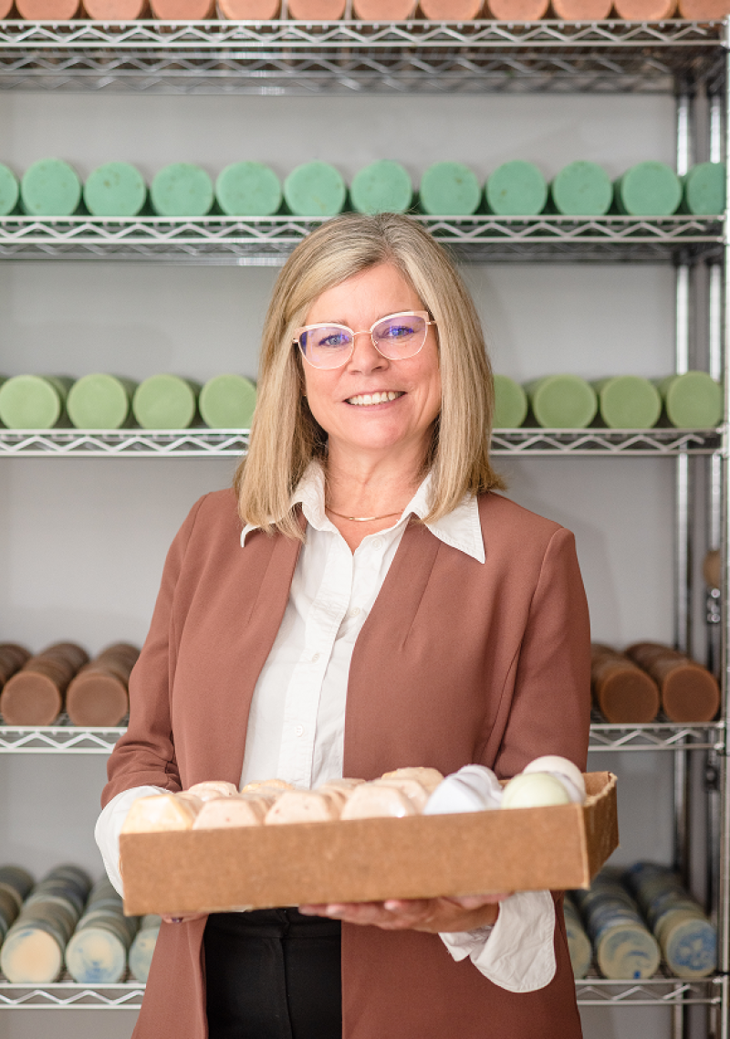 Person presenting tray of handmade soaps in workshop.