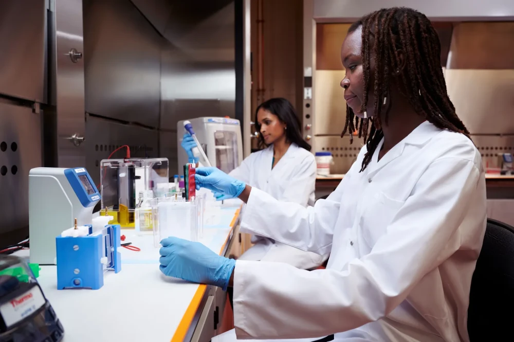 Two laboratory scientists processing test samples with research equipment and protective gloves.
